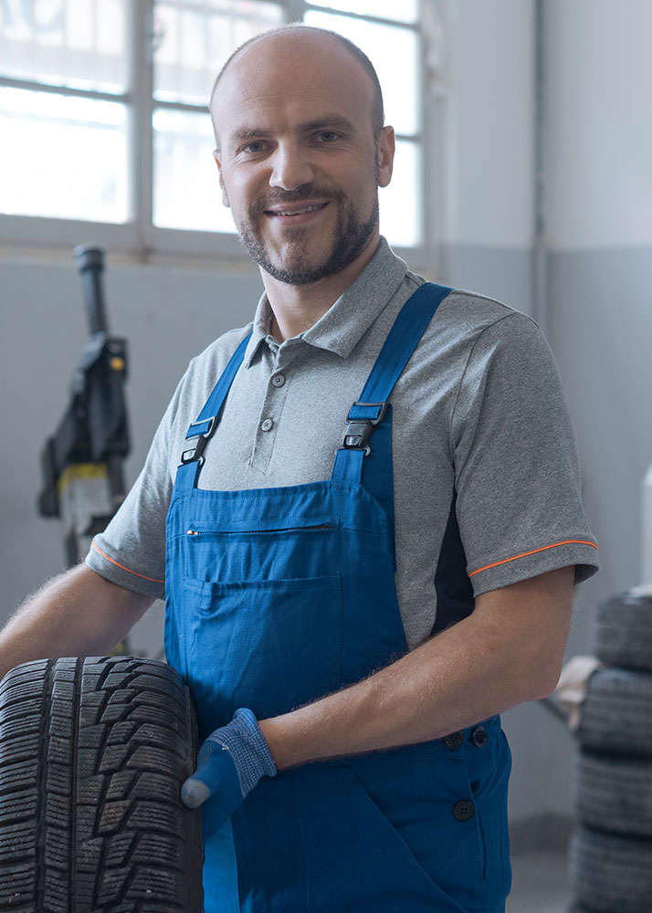 mechanic posing with a tire
